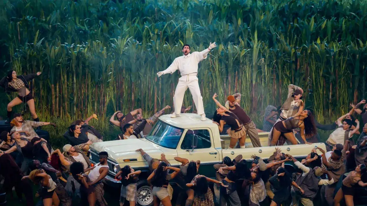 Super Bowl-artister dansar runt en pickup bland majsstjälkar. En artist står på taket.