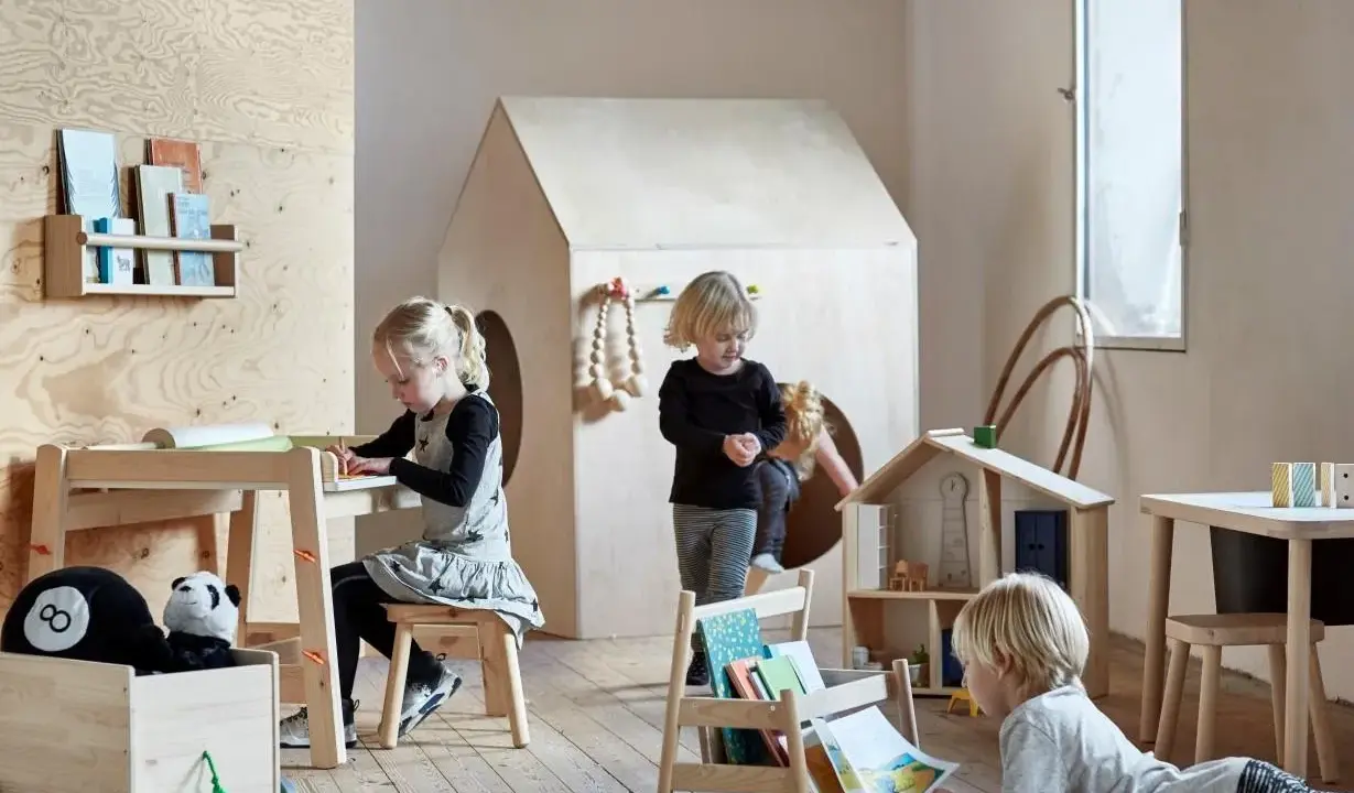 Dzieci bawią się i uczą przy stoliku sensorycznym IKEA FLISAT w pokoju zabaw.