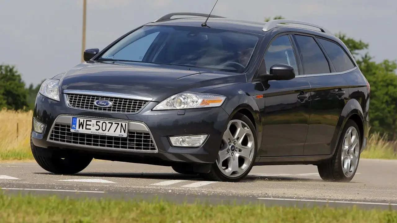 Ciemnoszary Ford Mondeo MK4 2.0 TDCI na drodze, z widocznym polem zboża w tle.