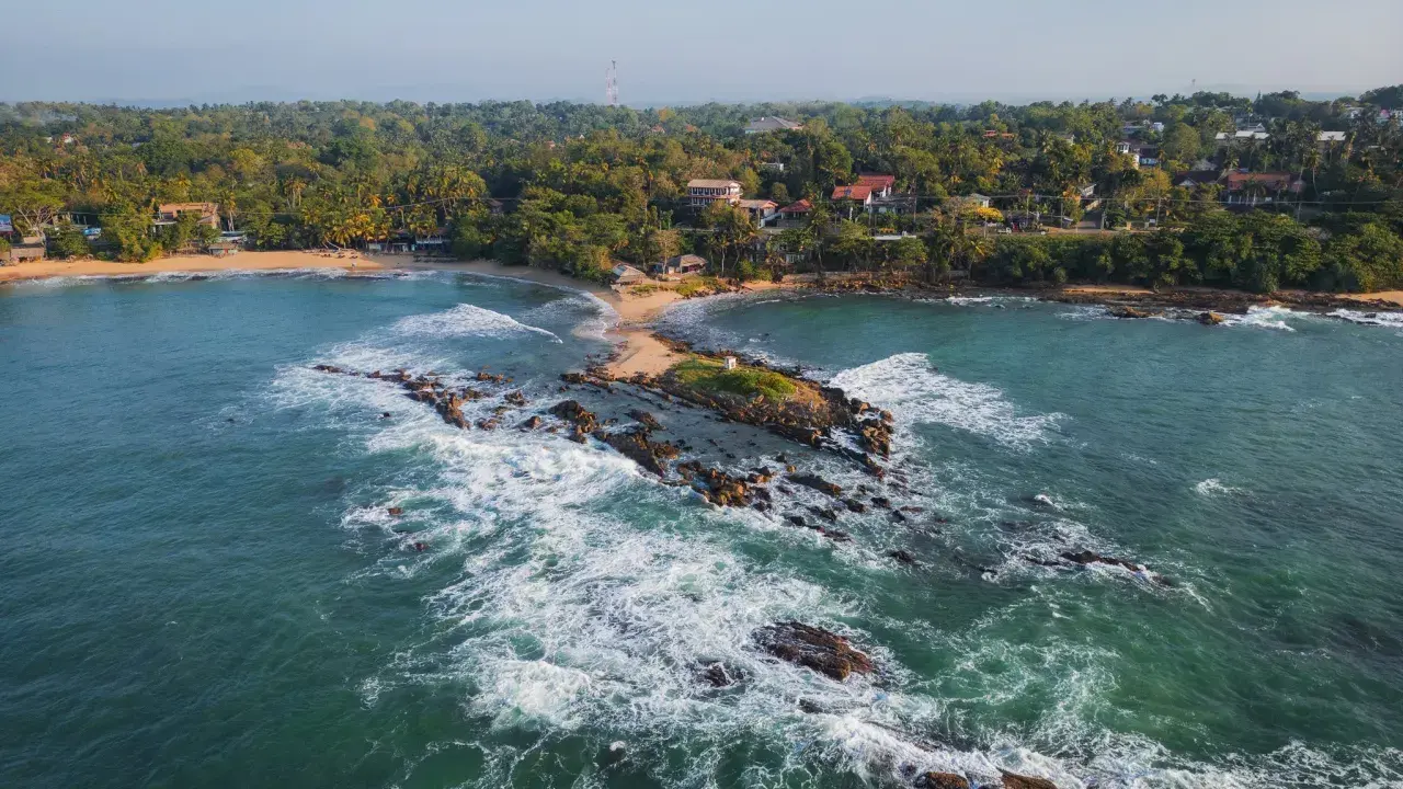 Malownicze wybrzeże, gdzie leży Sri Lanka. Tropikalna roślinność, plaże i skaliste wysepki w turkusowej wodzie.