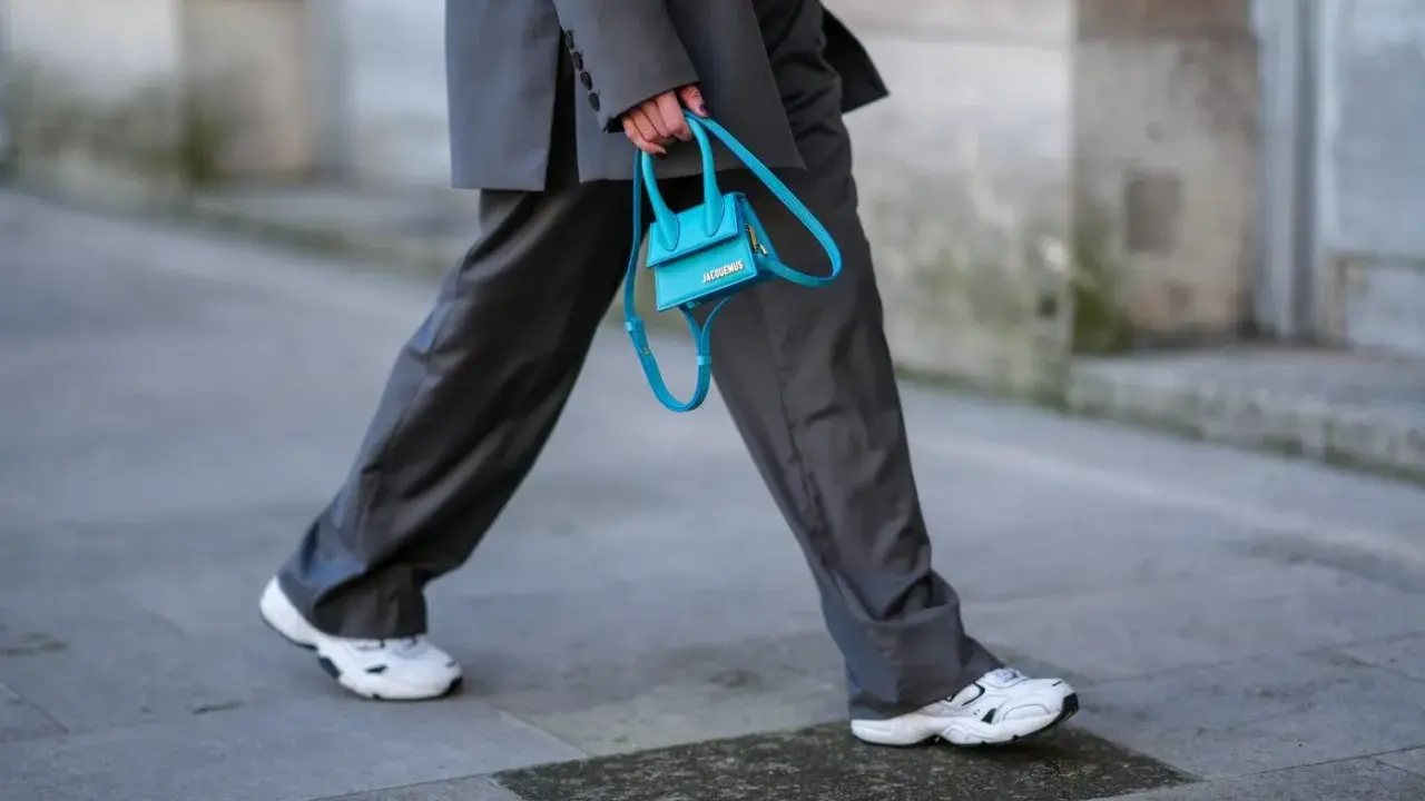 Elegancki damski garnitur w połączeniu z białymi sneakersami i turkusową torebką.