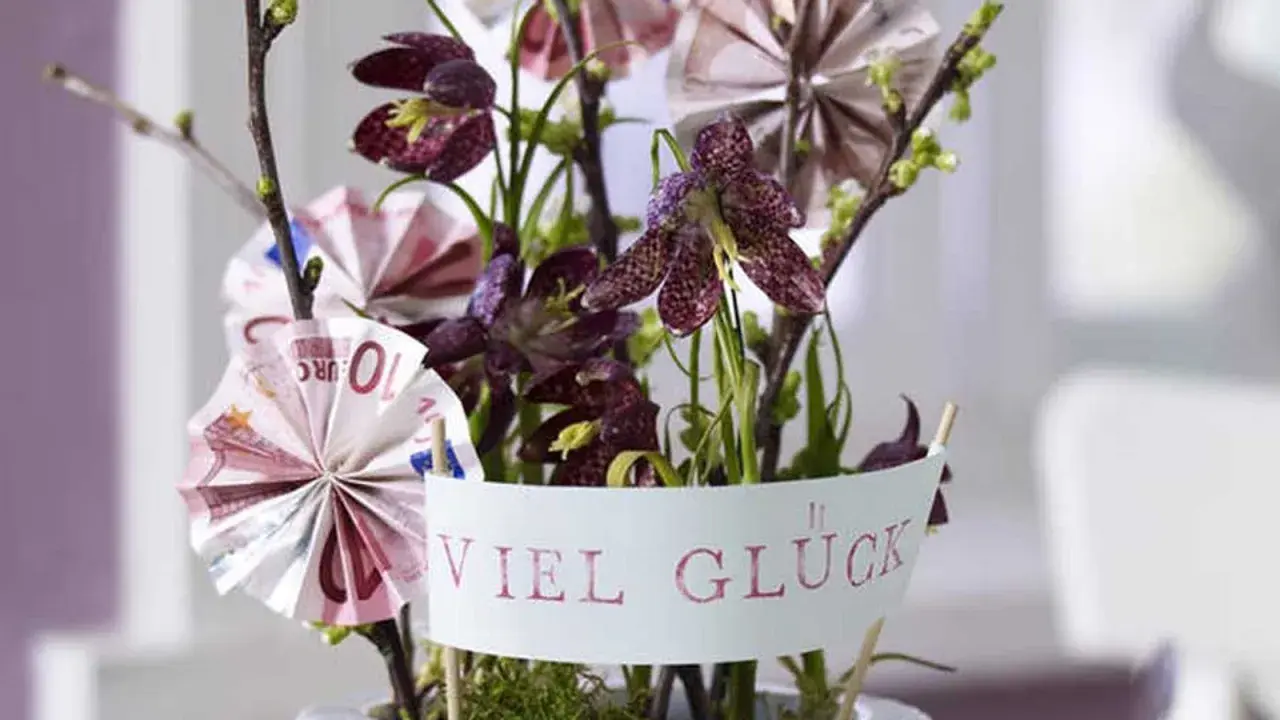 Kreative Geldgeschenke basteln: Ein Blumenarrangement mit gefalteten Euroscheinen und der Botschaft "Viel Glück".