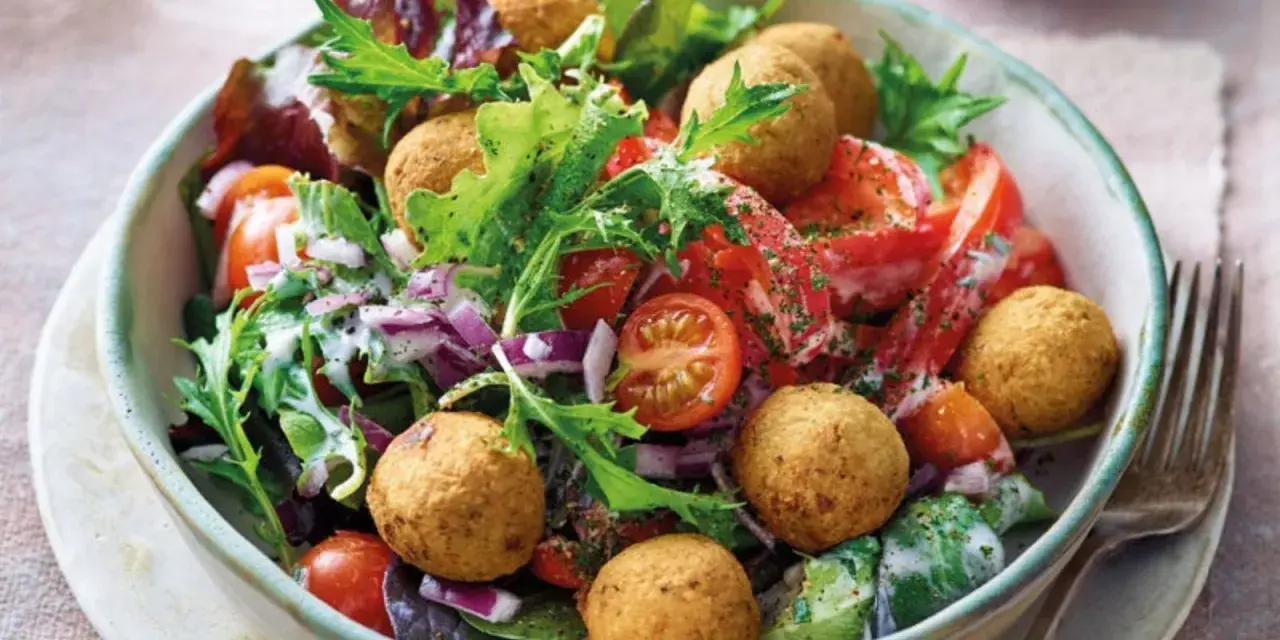 Bunter Salat mit Tomaten, Zwiebeln und Falafelbällchen. Ein schnelles gesundes Essen, das gut aussieht und schmeckt.