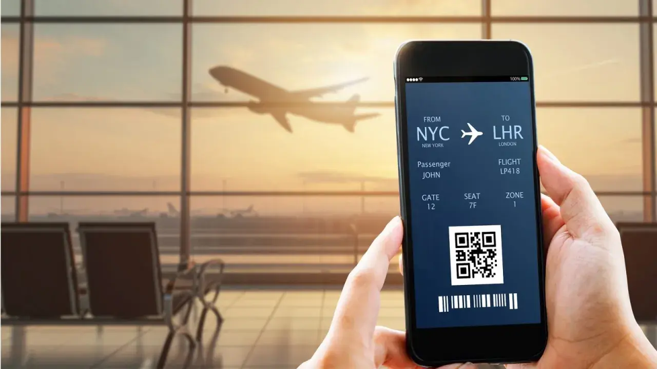 Bilet lotniczy na telefonie: lot z NYC do LHR, pasażer John, bramka 12. IATA co to? To kod lotniska.