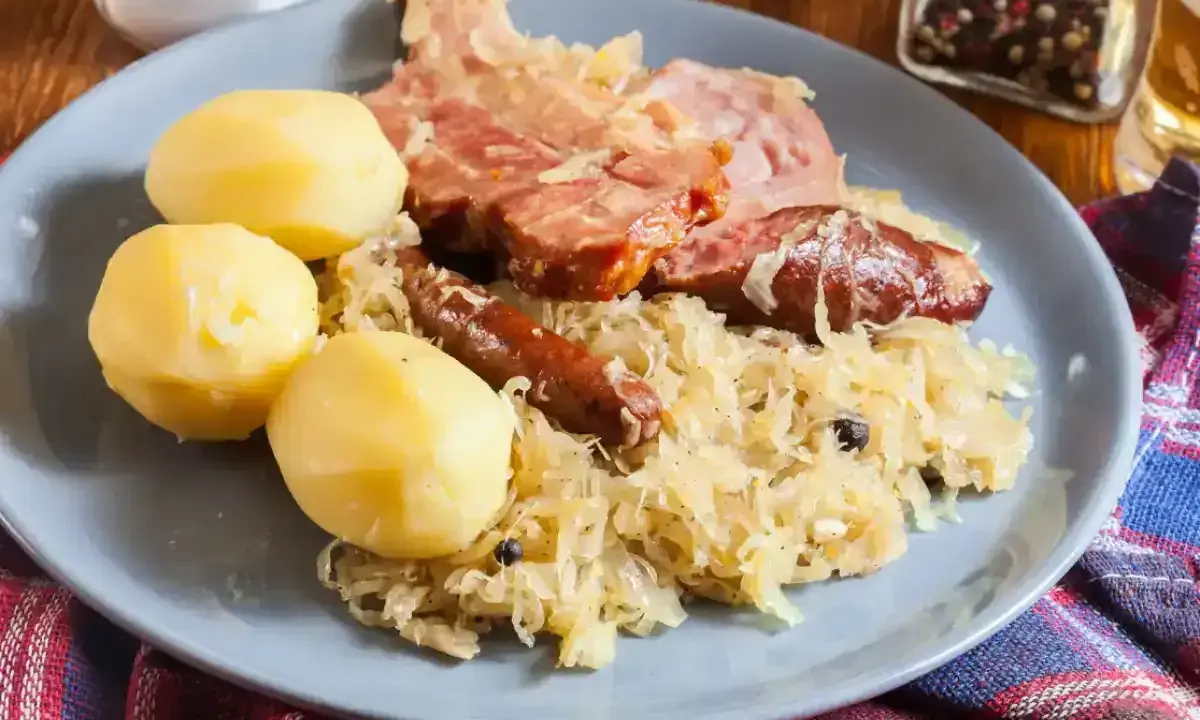 Une assiette de choucroute garnie, avec pommes de terre, saucisses et viande fumée. Un plat qui raconte une histoire culinaire.