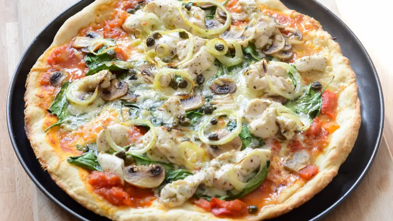 Pyszna pizza z kurczakiem, pieczarkami, szpinakiem i kaparami na cienkim cieście.