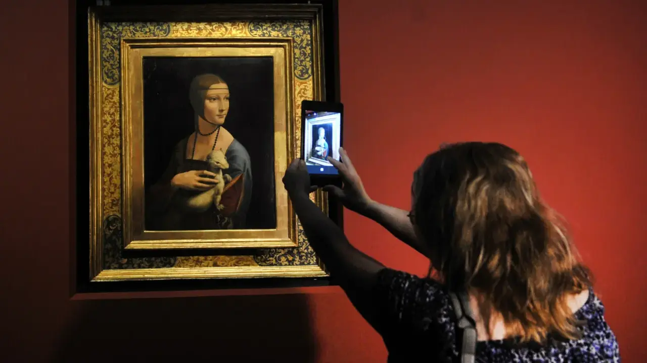 Dama z łasiczką w muzeum, gdzie jest? Kobieta robi zdjęcie słynnego obrazu telefonem.
