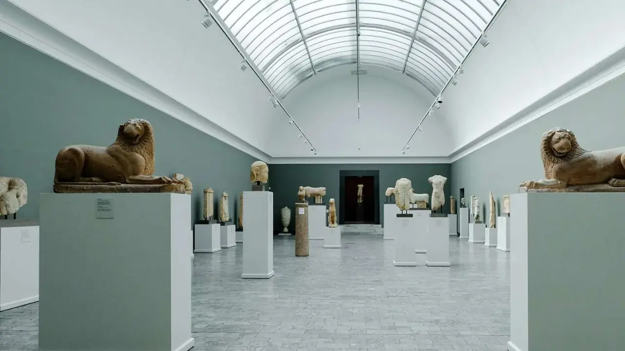 Starożytne rzeźby lwów i popiersi w muzeum w Kopenhadze, podświetlone przez świetlik w dachu.