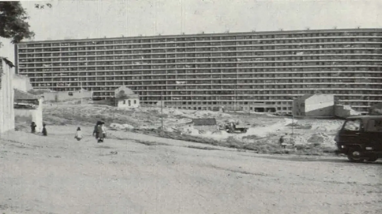 Edificio masivo de apartamentos en construcción, con obreros y vehículos en el sitio. Imagina cómo se veía cuando se inventó el cemento.