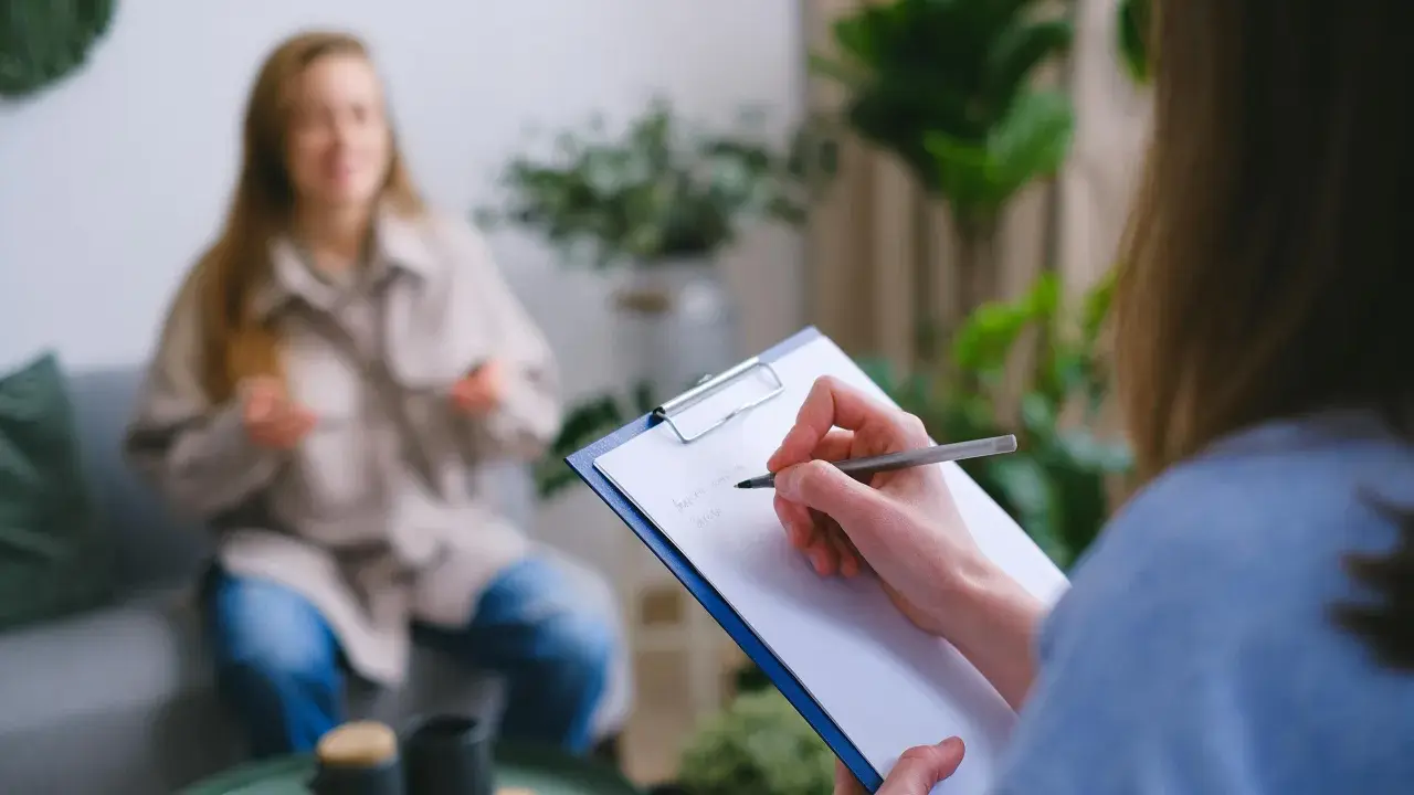 Psychologia kliniczna w praktyce: terapeuta notuje objawy pacjentki, która opowiada o swoich problemach.