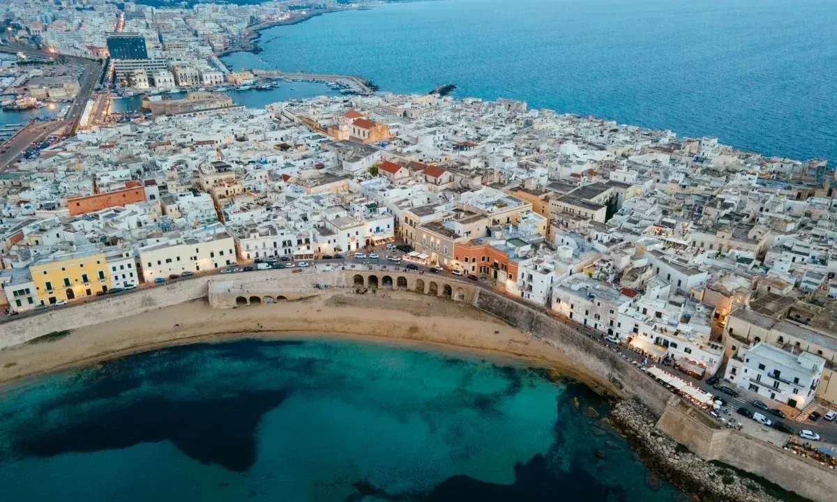Vista aerea del centro storico di Gallipoli, con case bianche, mare turchese e un arco sul lungomare. Scopri cosa vedere a Gallipoli centro storico.