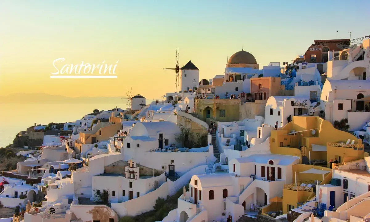 Zachód słońca nad Oia na Santorini. Czy warto? Białe domy, wiatraki i błękitne morze tworzą idylliczny krajobraz.