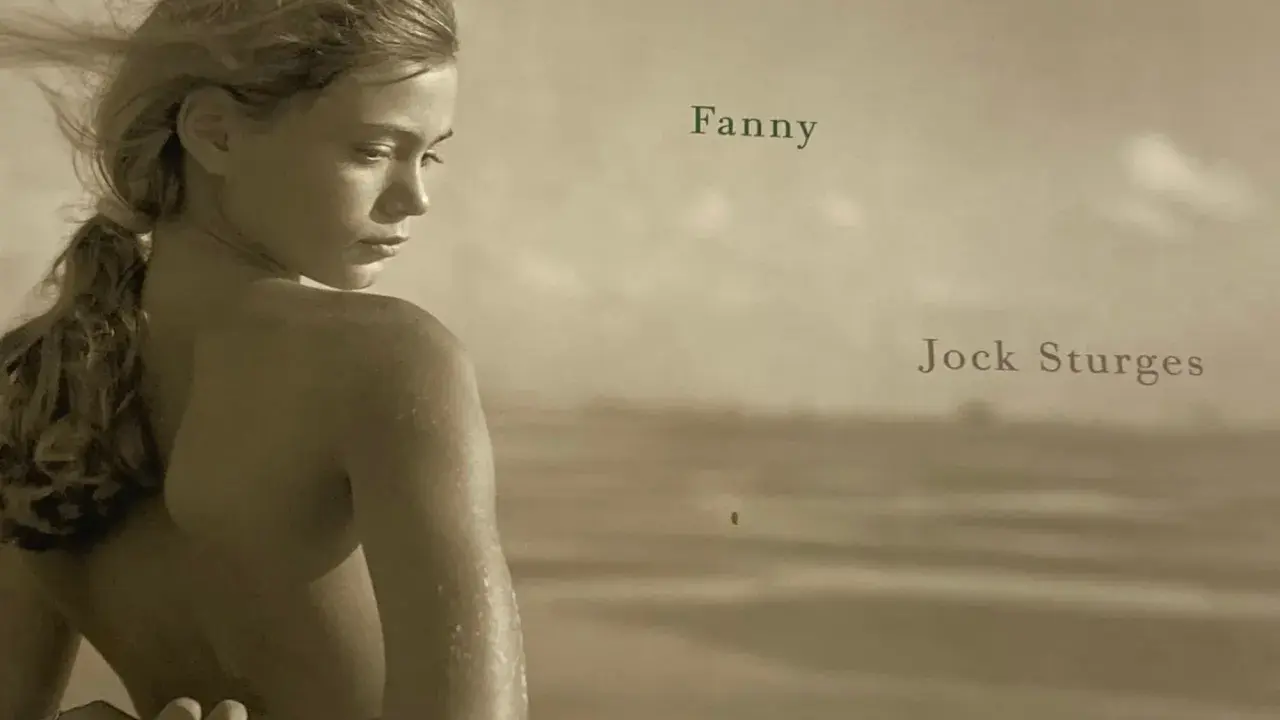 A young woman, Fanny, is captured by Jock Sturges on a beach, her hair blowing in the wind.