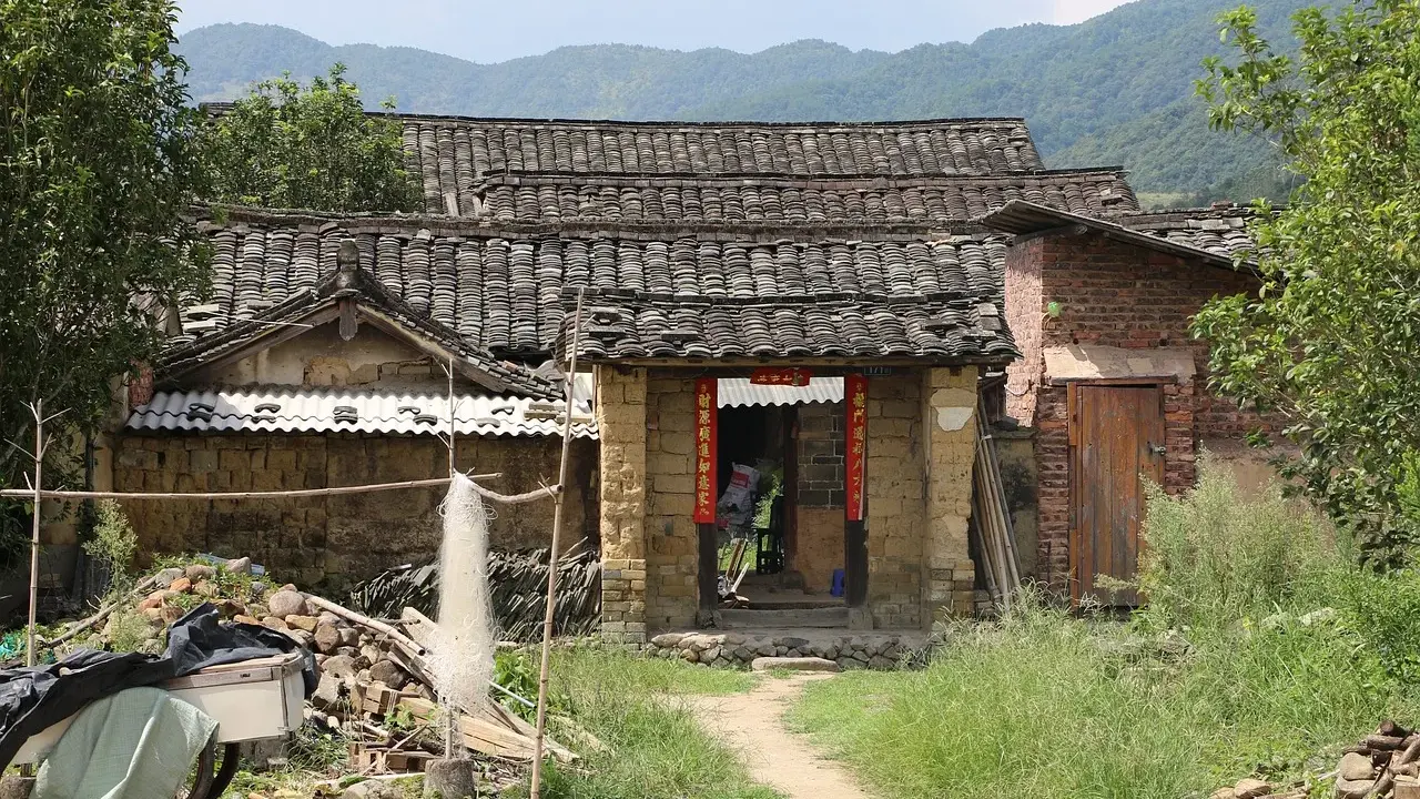 Maison en terre crue, toits de tuiles anciennes, montagnes en arrière-plan. Le prix d'une telle demeure est abordable.