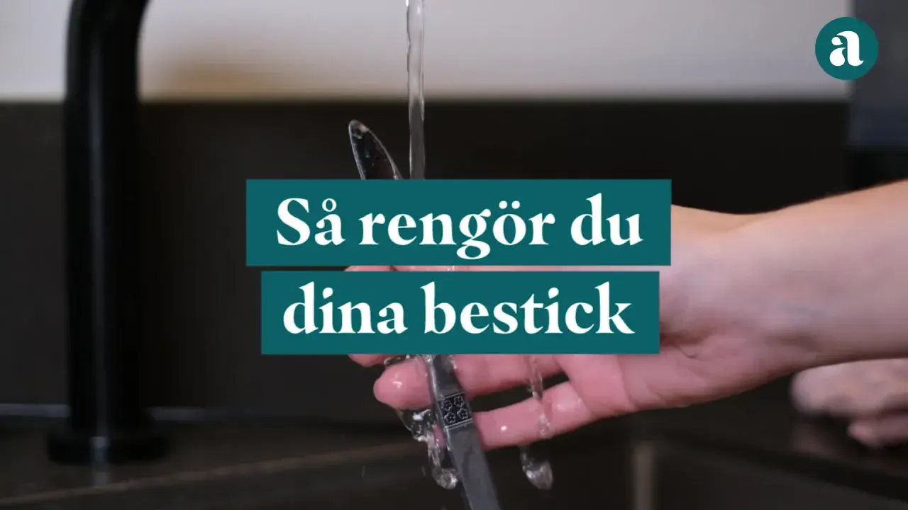 En hand håller ett bestick under rinnande vatten. Texten "Så rengör du dina bestick" visas.