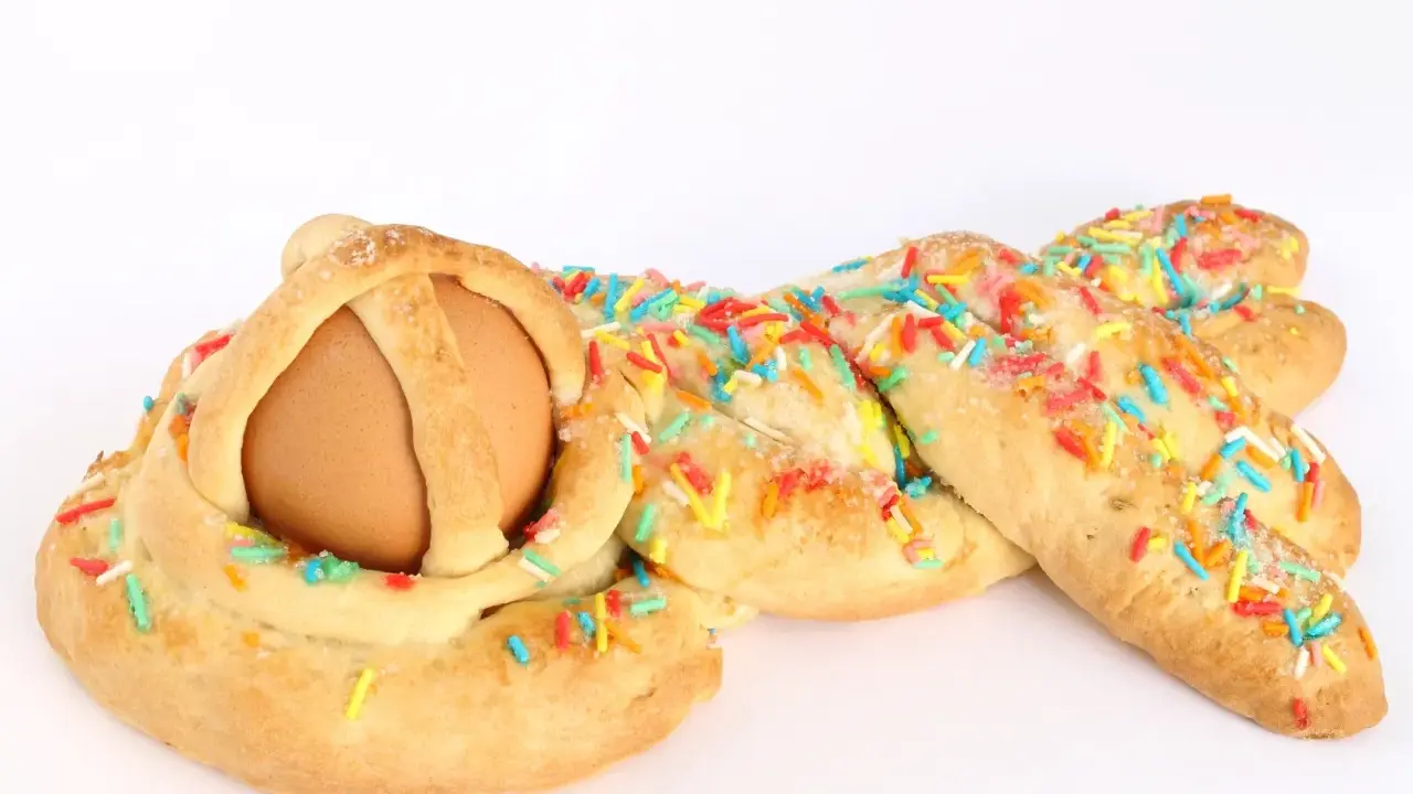 Dolci calabresi pasquali: un uovo incastonato in una treccia di pane dolce, decorata con zuccherini colorati.