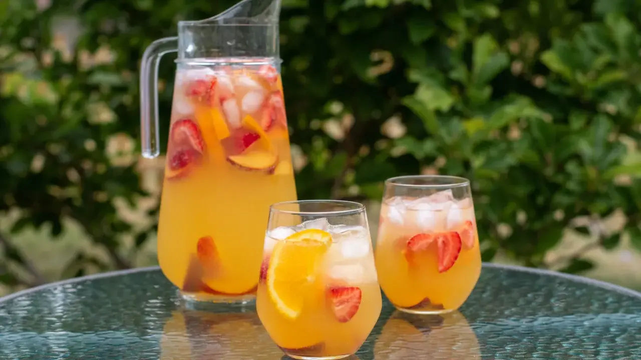 En karaff och två glas med en uppfriskande cava drink fylld med is, jordgubbar och apelsinskivor. Perfekt för en sommardag.