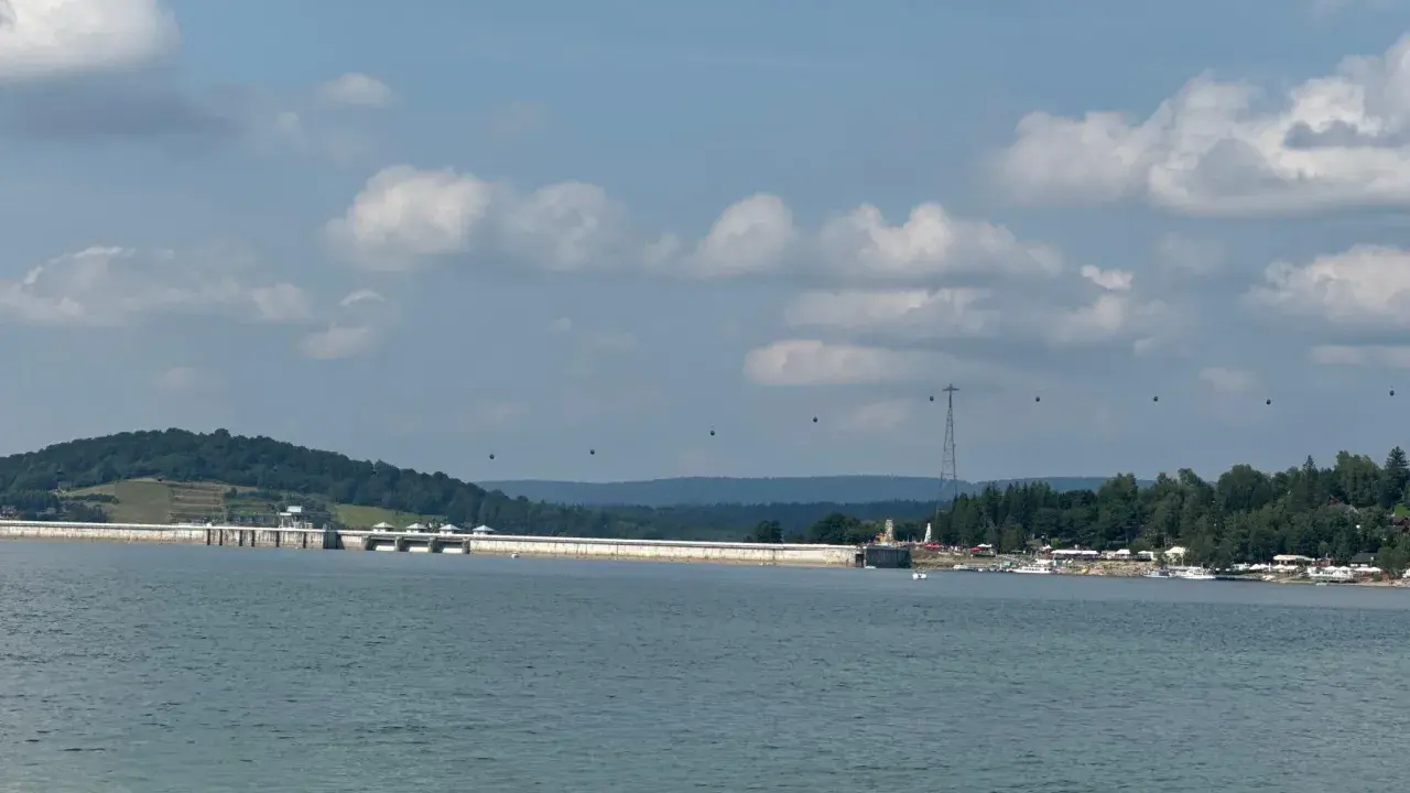 Widok na zaporę w Solinie, z widocznymi gondolami kolejki linowej i licznymi szlakami turystycznymi w tle.