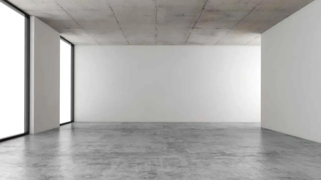 Espacio minimalista con paredes blancas, techo de hormigón y suelo de **cemento pulido** que refleja la luz.