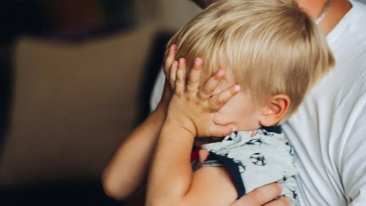 2,5-letnie dziecko budzi się w nocy z płaczem, ukrywając twarz w dłoniach. Tata tuli go, próbując uspokoić.