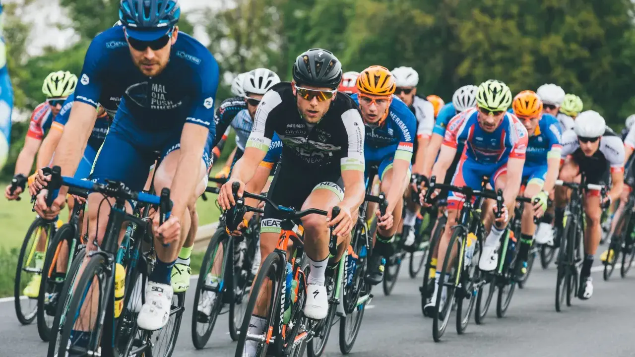 Ciclisti in gara, concentrati e determinati, seguono le loro tabelle allenamento ciclismo per raggiungere la vittoria.