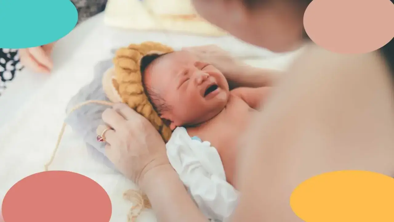 Un recién nacido no duerme, llora desconsoladamente mientras una mano le acaricia la cabeza.