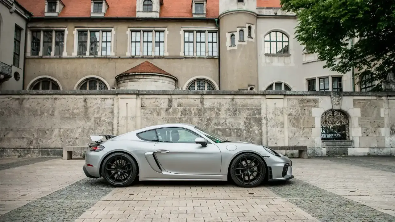 Silberner Porsche GT4 vor historischer Kulisse. Die technischen Daten dieses Sportwagens sind beeindruckend.