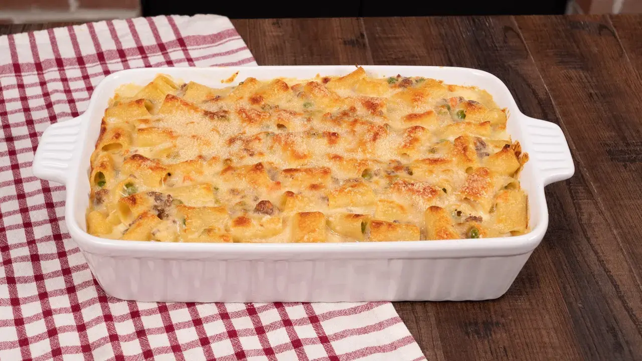 Un invitante pasta al forno bianca, con maccheroni dorati, piselli e carne macinata, gratinata al punto giusto.