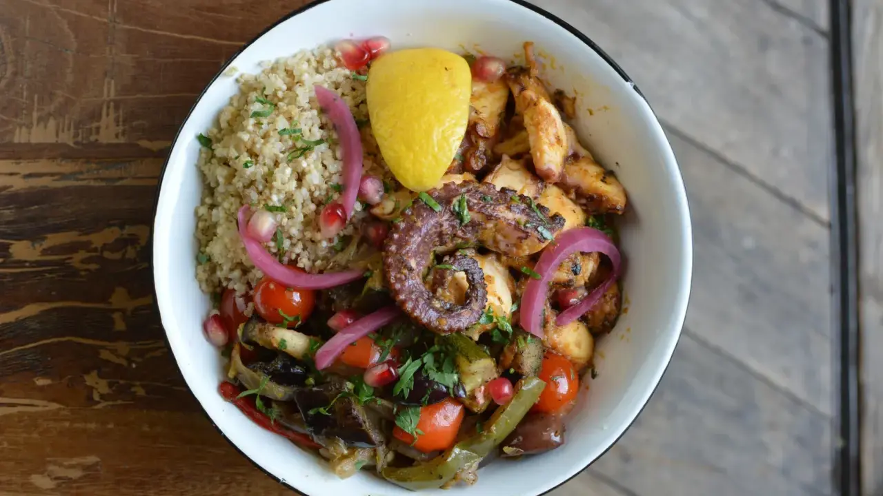 Un plat coloré avec du poulpe grillé, du quinoa, des légumes rôtis et une touche de citron. La marinade pour poulpe grillé a sublimé ce plat.