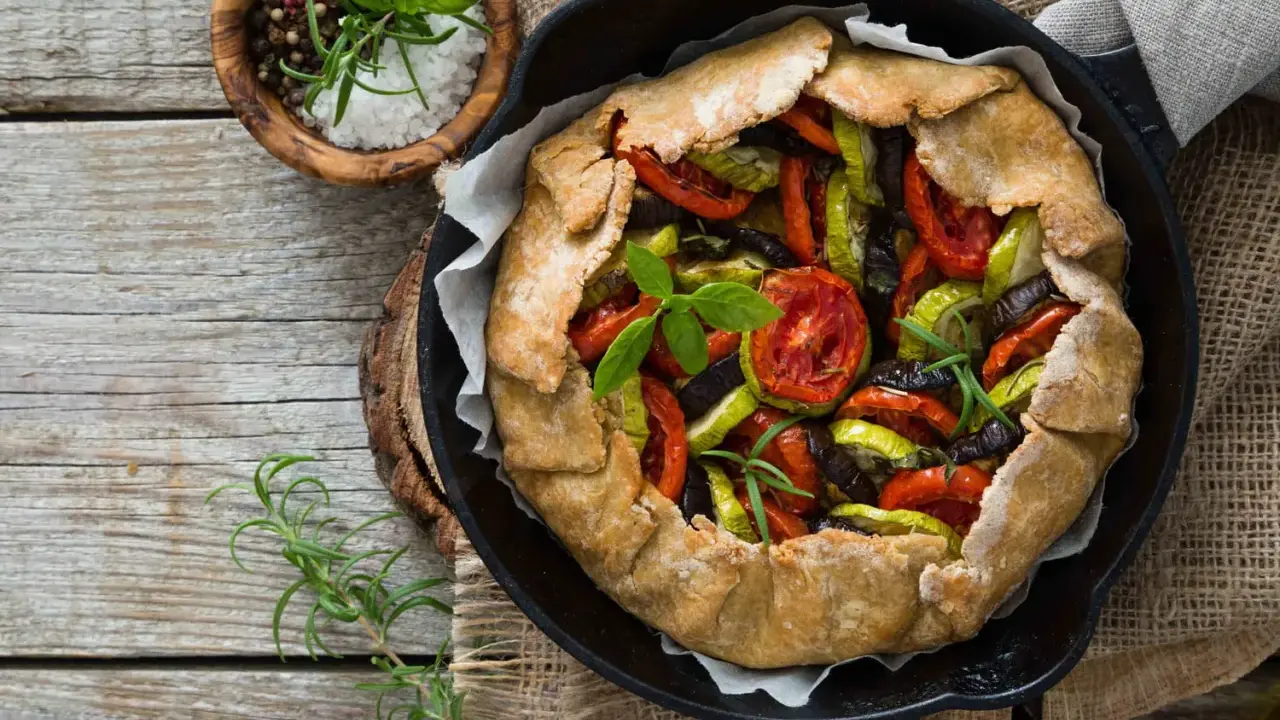 Tarte aux légumes colorée, garnie de tomates, courgettes et aubergines, prête à être dégustée.