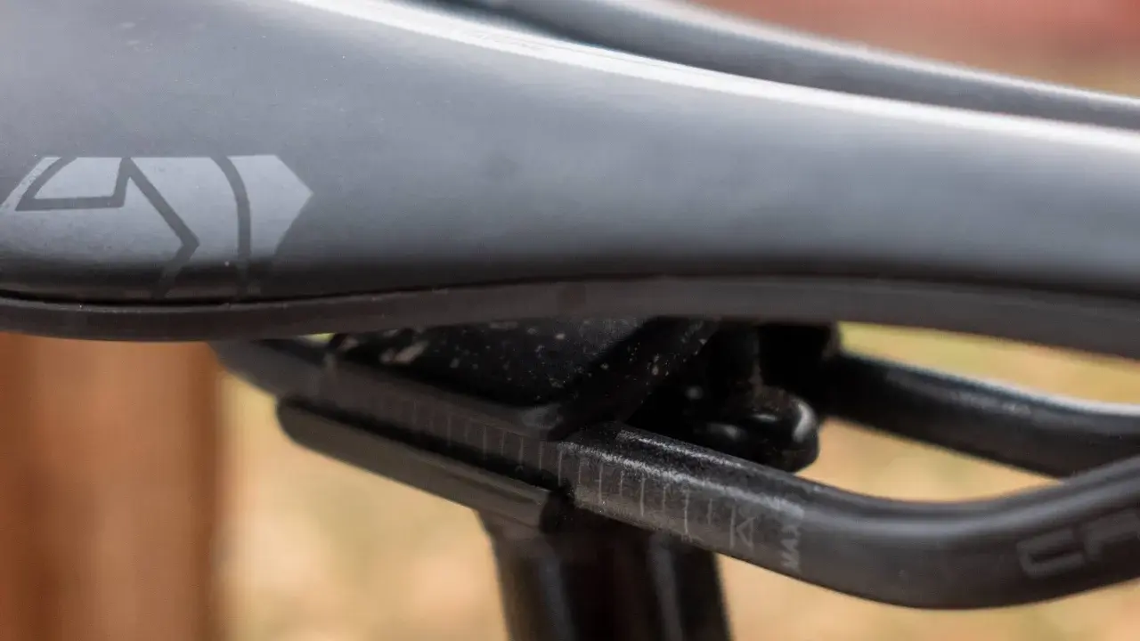 Szukasz idealne siodełko do mtb? Zobacz zbliżenie na czarne siodełko rowerowe z logo i oznaczeniami regulacji.