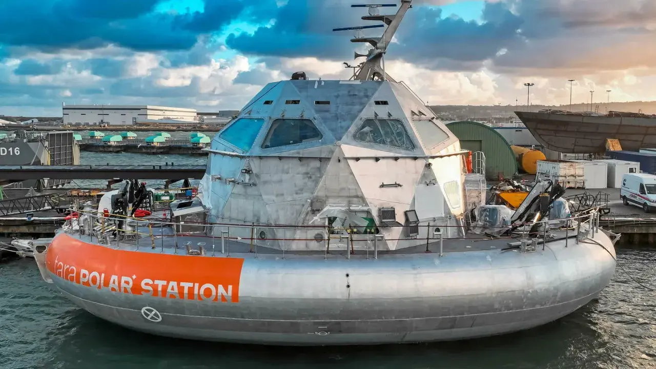 Le bateau Tara Polar Station, une station polaire futuriste, est amarré dans un port sous un ciel dramatique.