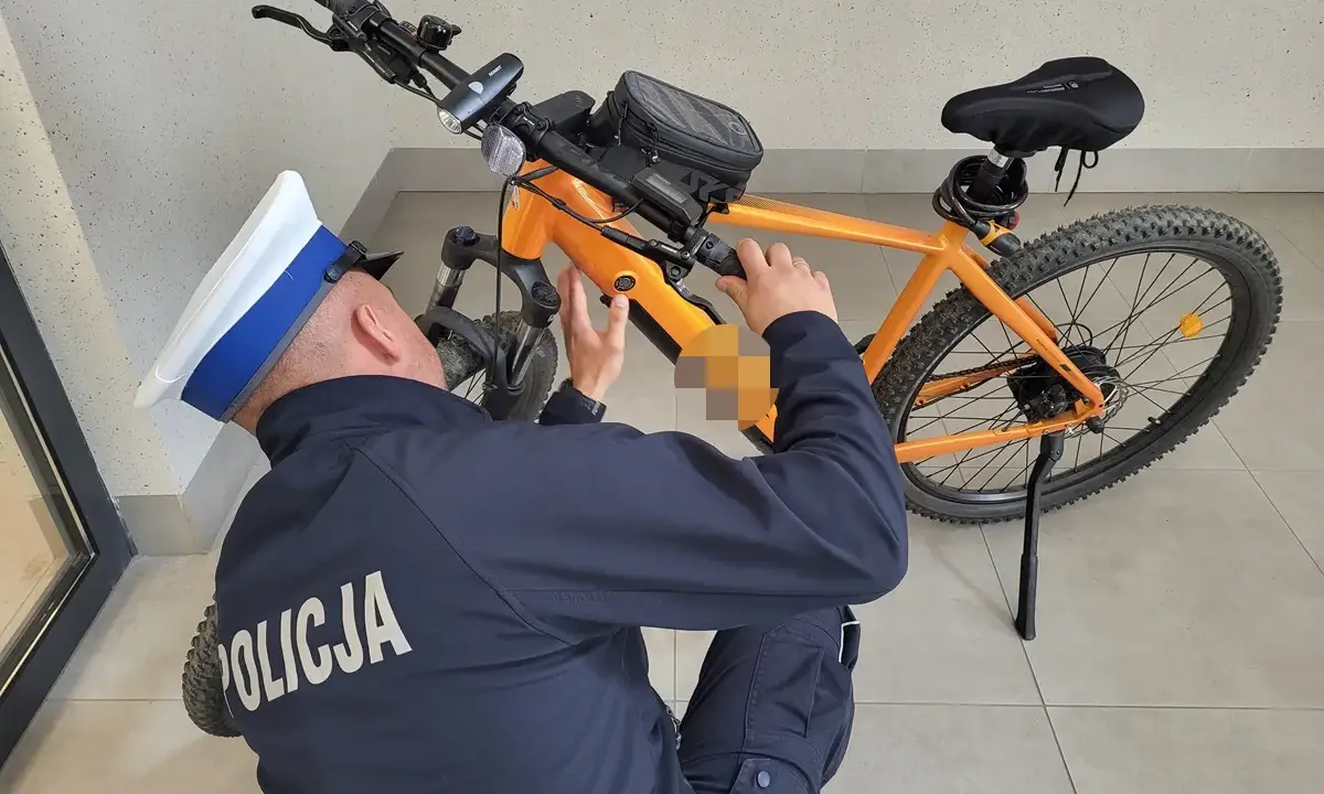 Policjant sprawdza, czy na rower elektryczny trzeba mieć prawo jazdy. Pomarańczowy rower z sakwą na kierownicy.