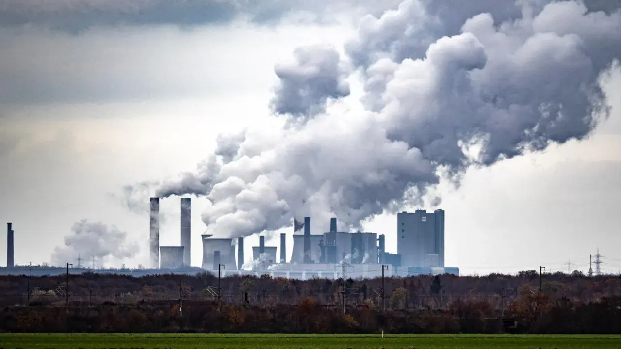 Rauchschwaden steigen aus einem Kraftwerk auf und symbolisieren die historischen CO2-Emissionen, die die Umwelt belasten.
