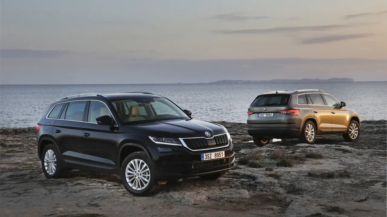 Dwa SUV-y Skoda Kodiaq 2024 na skalistym wybrzeżu. Jeden czarny, drugi w kolorze złota.