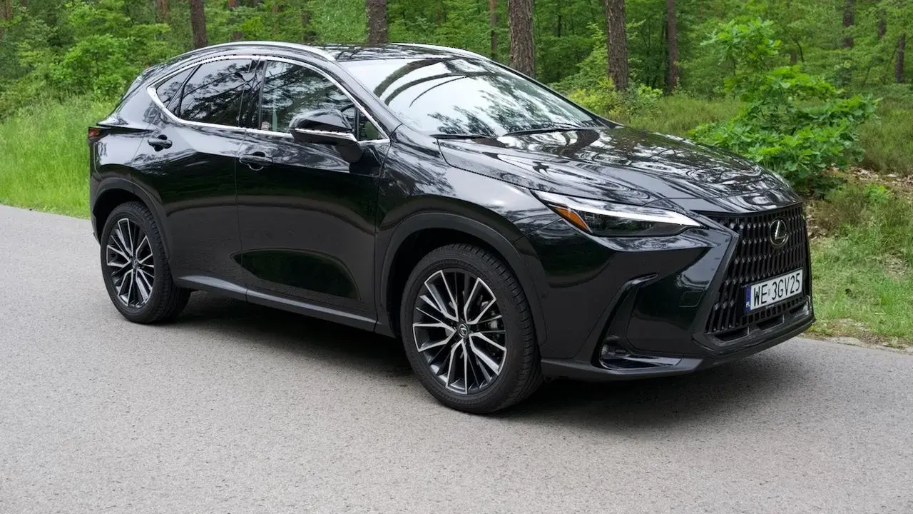 Elegancki, czarny Lexus NX 350h na tle leśnej drogi.