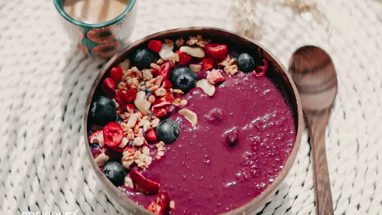 Fruchtige Acai-Bowl mit Blaubeeren, Granola und Beeren – perfekt, wenn du deine eigene Bowl selber machen möchtest. Dazu eine Tasse Kaffee.