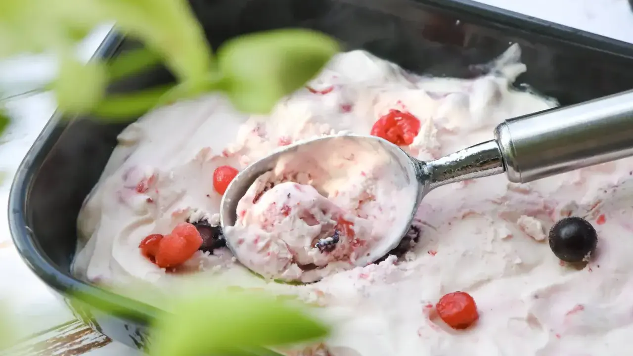 Glace au yaourt italienne aux fruits rouges, servie dans un bac avec une cuillère. Parfait pour une recette facile et rafraîchissante.