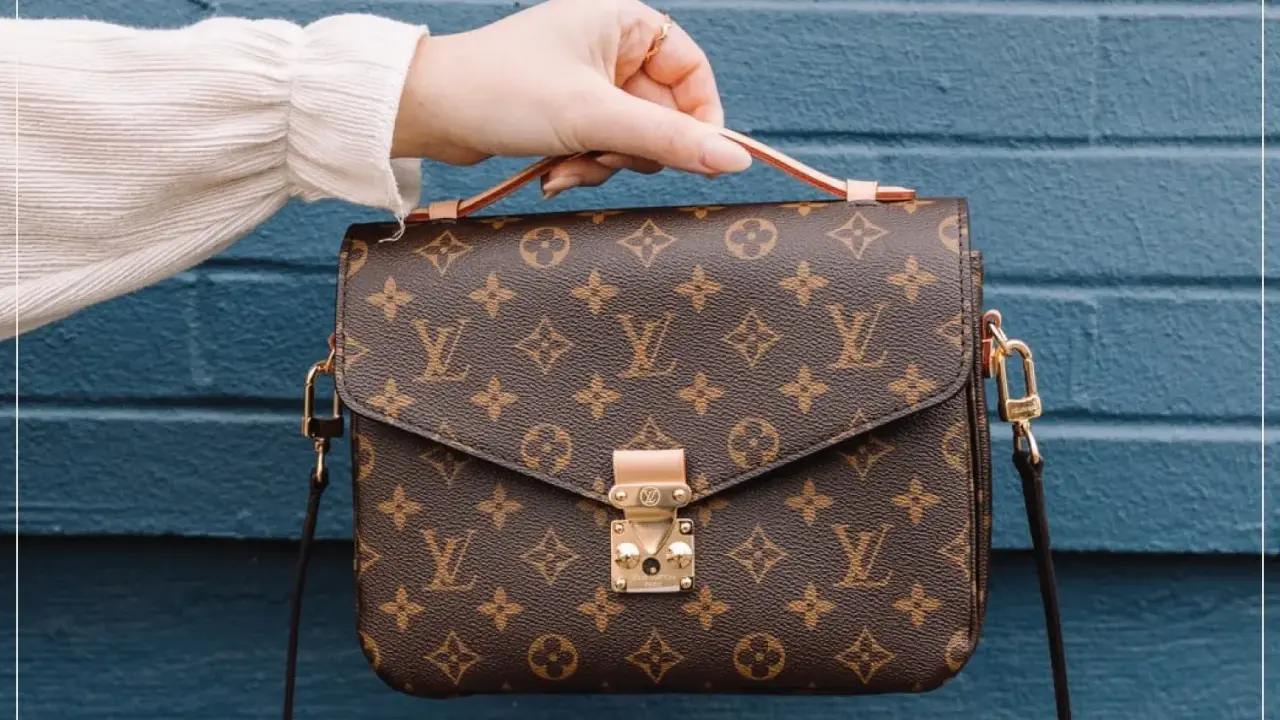 Eine Hand hält eine braune Louis Vuitton Tasche mit Monogramm-Muster. So erkennst du ein louis vuitton original.
