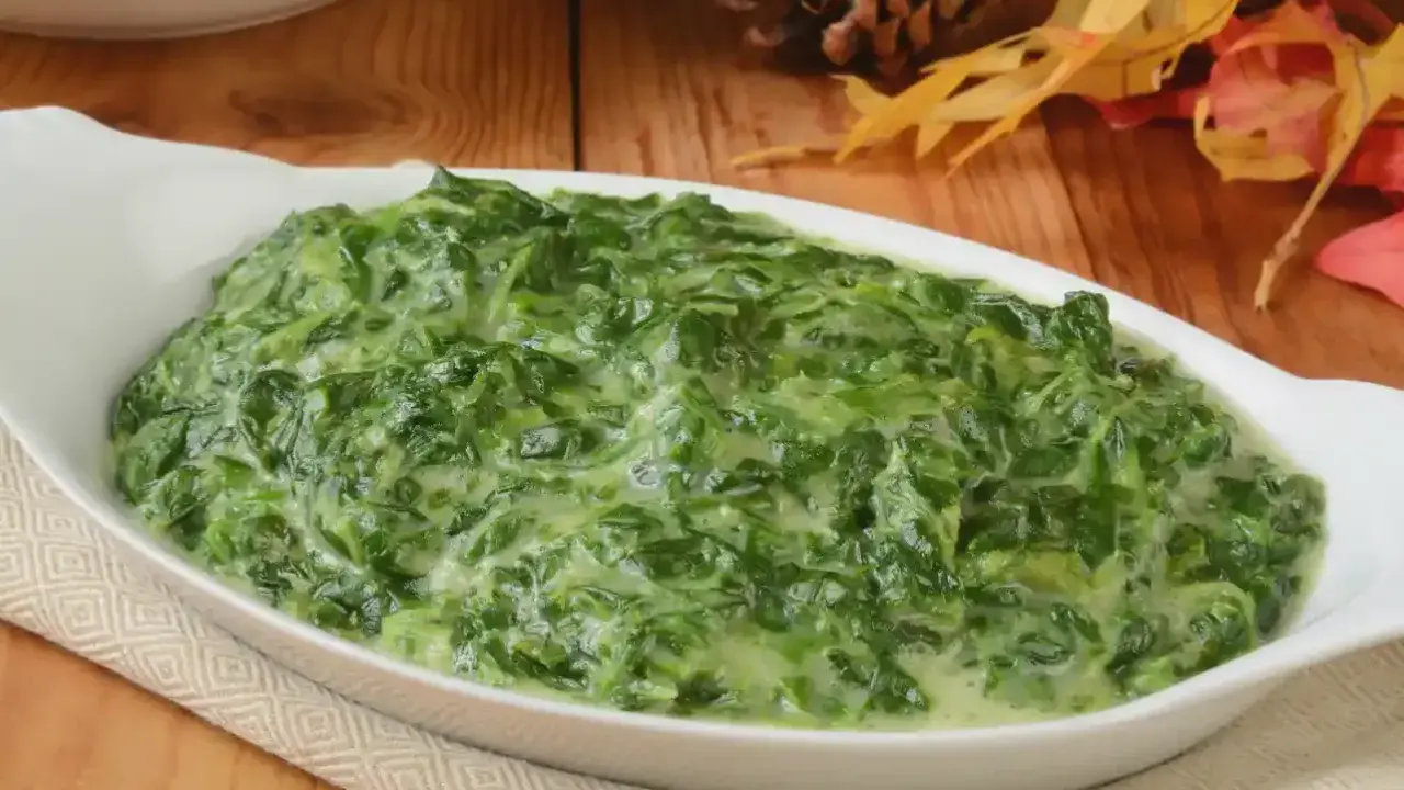 Un plat de épinards à la crème crémeux et appétissant dans un plat blanc, prêt à être dégusté.