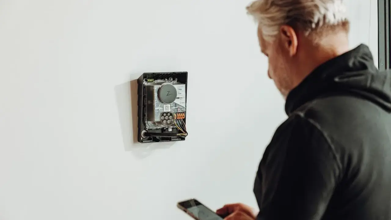 Man med mobil kontrollerar enhet för energisk lastbalansering via wifi.