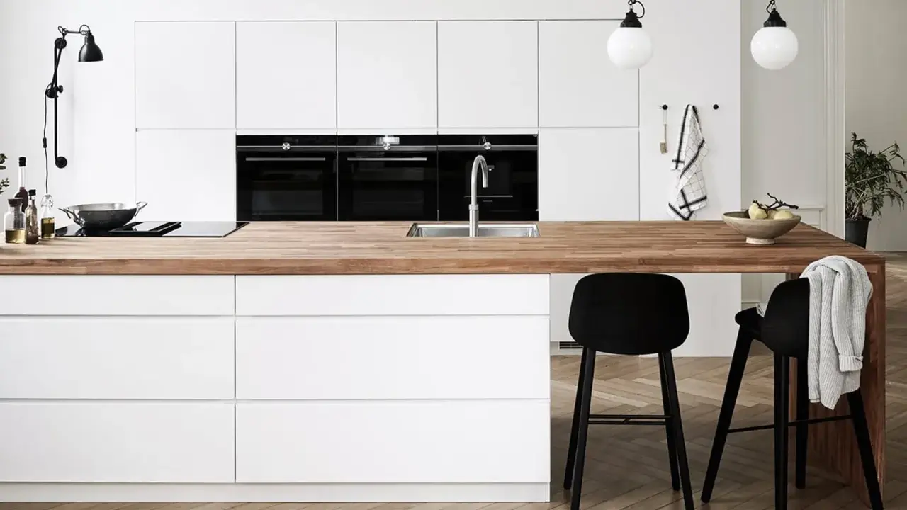Un plan de travail en bois chaleureux contraste avec les meubles de cuisine blancs. Quelle couleur de plan de travail pour une cuisine blanche ? Le bois est une option parfaite.