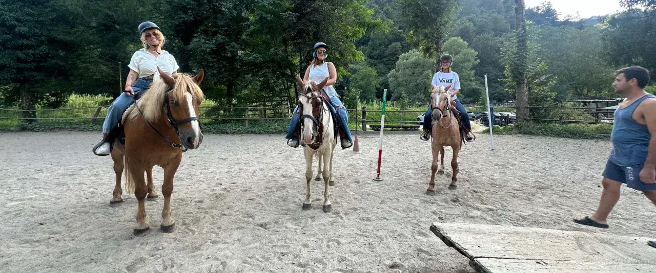 Tre donne si godono una passeggiata a cavallo in Lombardia, con un uomo che le osserva.