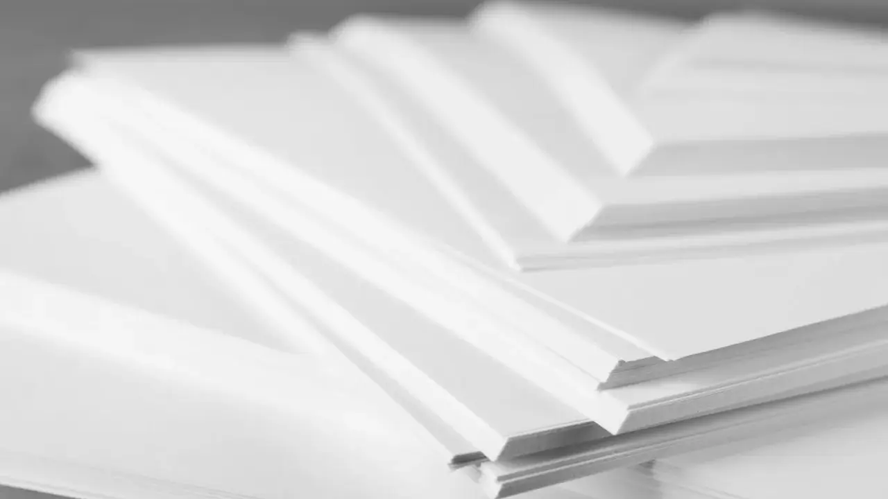 Stosy białego papieru offsetowego ułożone warstwowo, tworząc geometryczne kształty.