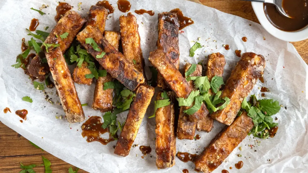 Marinierter Tofu, knusprig gebraten und mit einer dunklen Sauce beträufelt, garniert mit frischem Koriander. Perfekt zum Dippen!