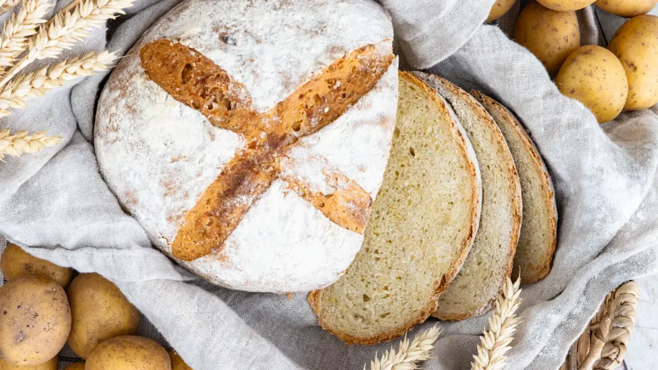 Frisch gebackenes Kartoffelbrot, aufgeschnitten und mit Kartoffeln und Weizenähren dekoriert. Ein tolles Rezept für Kartoffelbrot!
