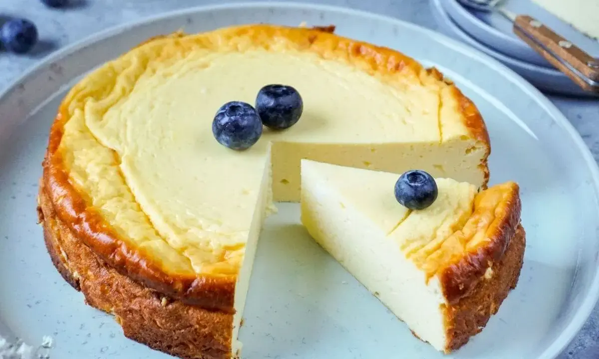 Ein köstlicher low carb Kuchen mit Blaubeeren, der auf einem Teller serviert wird. Ein Stück ist bereits herausgeschnitten.
