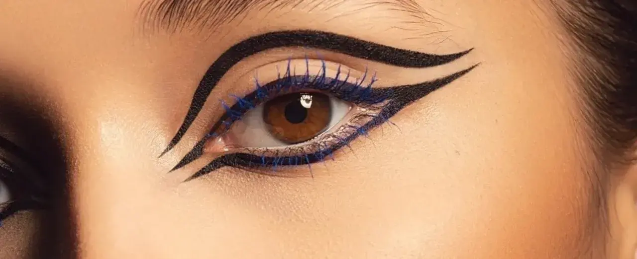 Ojo con delineado dramático y pestañas azules, inspirado en el maquillaje egipcio.