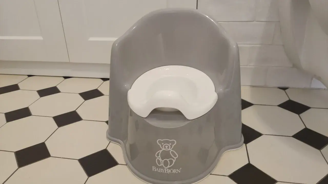 Szary nocnik BabyBjörn z białym siedziskiem, symbolizujący nowy etap w procesie odpieluchowania.