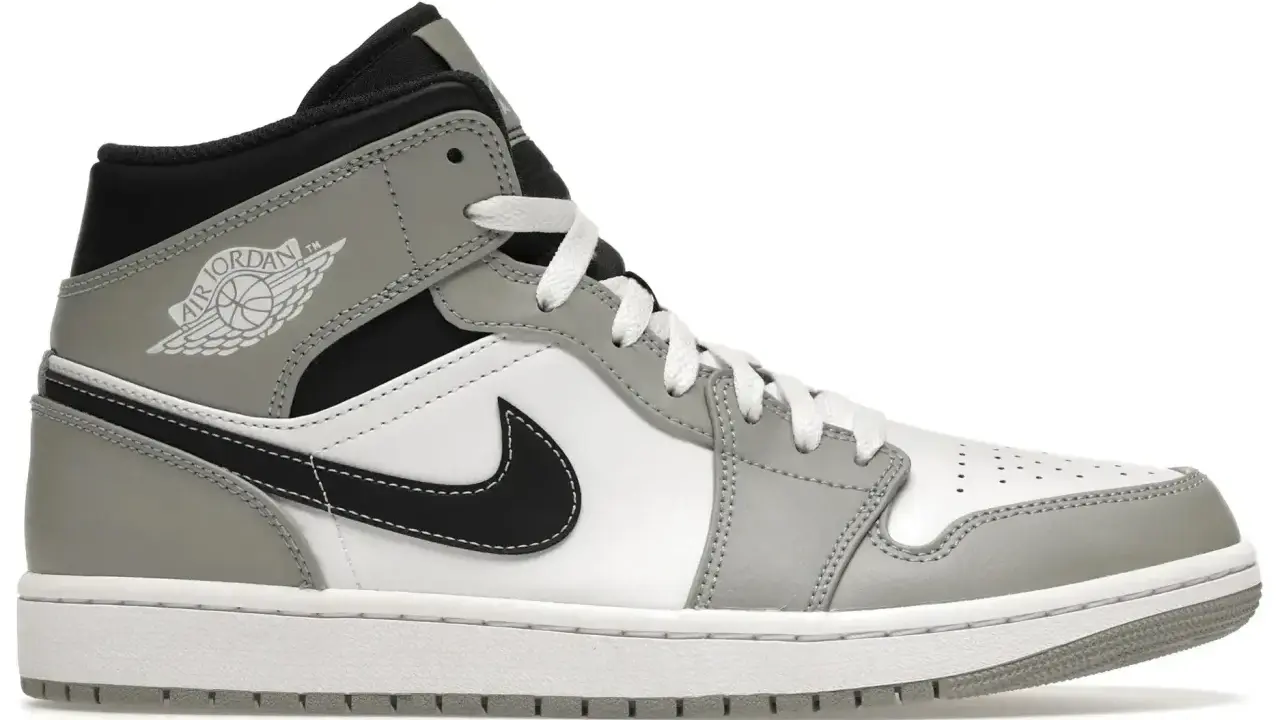Szary i biały but sportowy, przypominający jordan 1 fake, z czarnym logo i sznurówkami.